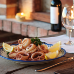 A plate of fried baby squid with lemon wedges and parsley.