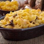 A freshly baked macaroni and cheese dish with a golden breadcrumb crust served in a vintage casserole dish.