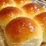 Freshly baked soft and buttery dinner rolls on a wooden table