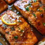 A beautifully baked salmon fillet garnished with herbs and lemon slices.