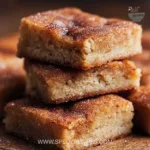 Delicious cinnamon sugar blondies served on a plate, topped with a sprinkle of cinnamon.