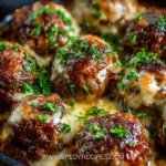 Crockpot French Onion Meatballs served on a plate with melted cheese and herbs.