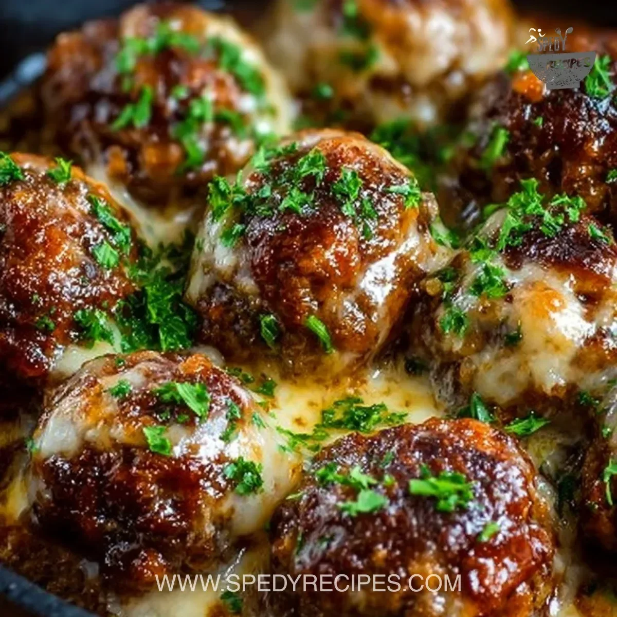 Crockpot French Onion Meatballs served on a plate with melted cheese and herbs.