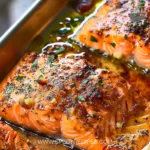 A delicious plate of oven baked salmon garnished with herbs and lemon slices.