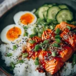 Honey Sriracha Salmon Bowl with vegetables and rice garnished with sesame seeds