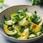 Fresh avocado salad with mixed vegetables and dressing served in a bowl