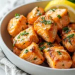 Air fryer salmon bites served on a plate with lemon wedges