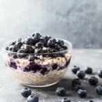 Bowl of blueberry overnight oats topped with fresh blueberries and almonds.