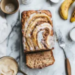 Sliced cinnamon roll banana bread on a wooden board with cinnamon swirls