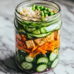 Creamy Asian cucumber salad bowl topped with sesame seeds and fresh herbs