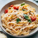 Creamy tomato garlic pasta garnished with fresh basil and Parmesan cheese