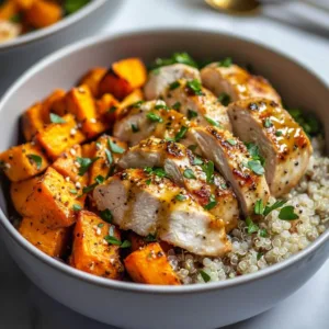 Delicious Maple Dijon Chicken served in a bowl with sweet potatoes and greens.