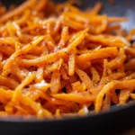 Healthy sweet potato hash browns served on a plate with fresh herbs.