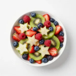 A vibrant fruit salad in a clear bowl, featuring layers of red strawberries, white banana slices, and blue blueberries, arranged to resemble the American flag.
