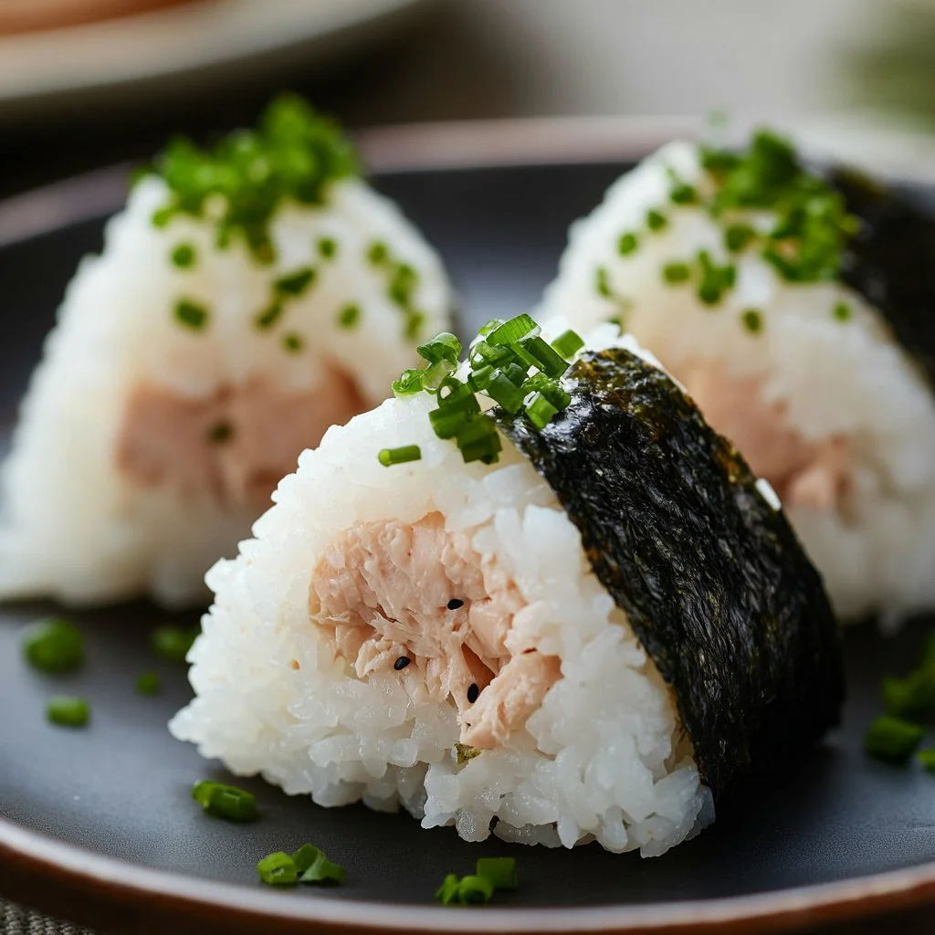 Tuna rice ball served on a plate, garnished with sesame seeds and green onions.