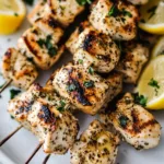 Yogurt marinated chicken kebabs on a grill, garnished with veggies.