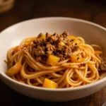 A plate of spaghetti with a messy sauce and garnished with herbs