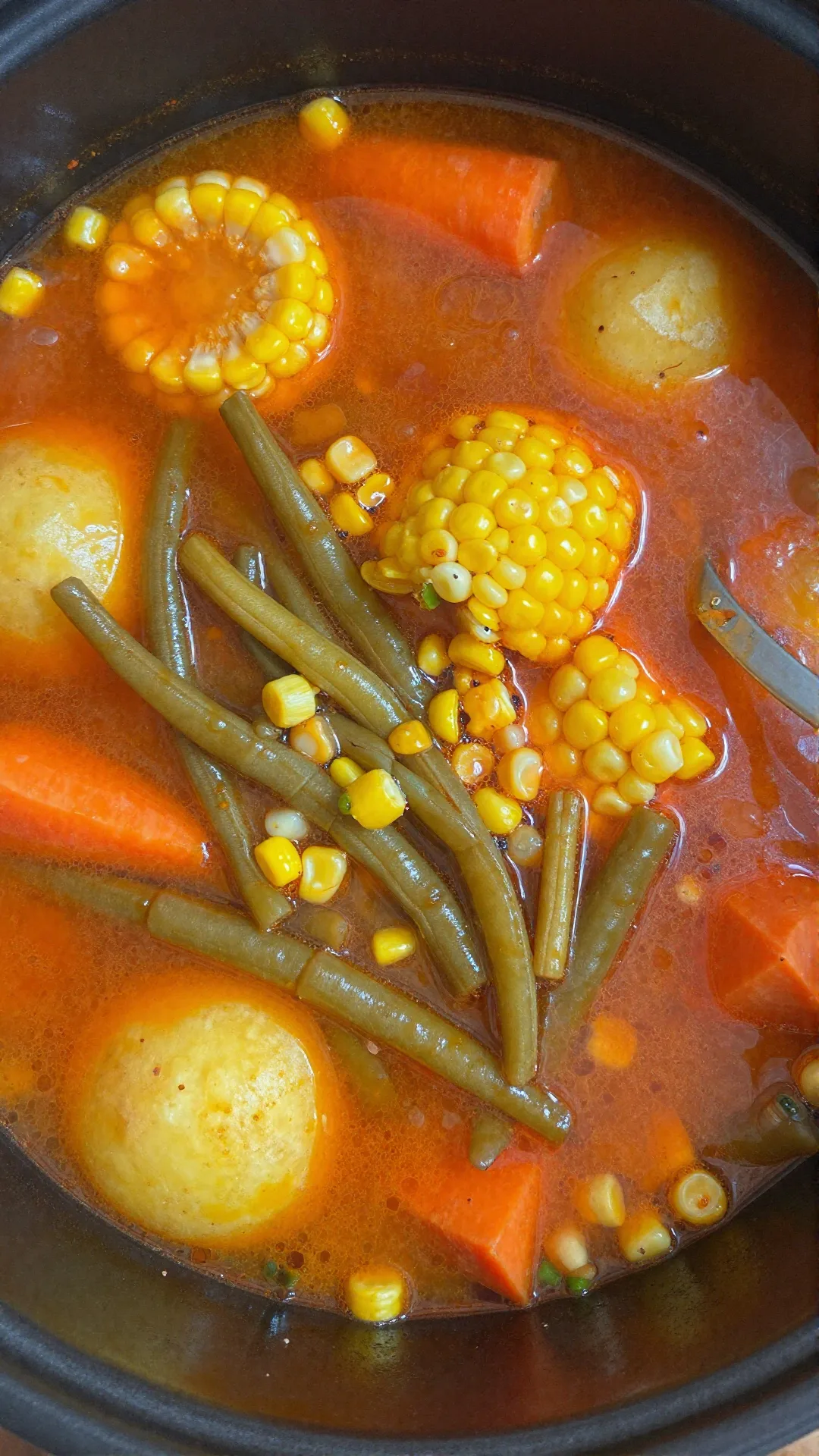 A bowl of hearty vegetable soup served with fresh herbs and bread.